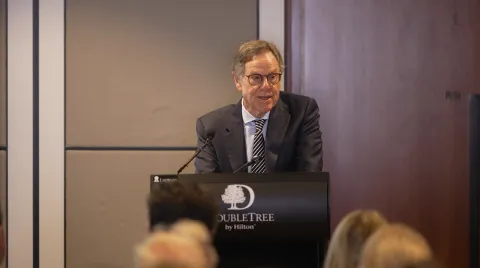 Commissioner Corboy standing behind a lectern speaking