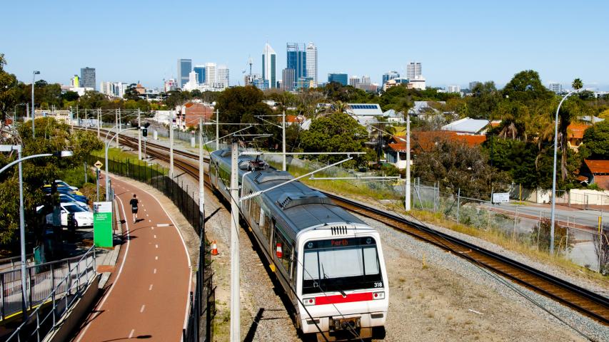 Train on train tracks, with Perth skyline in the background